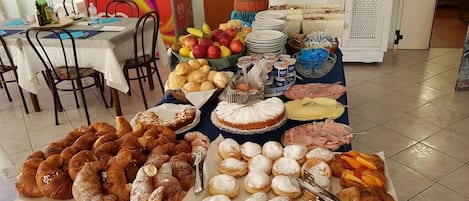A buffet table with various food items, including pastries, fruits, and condiments.