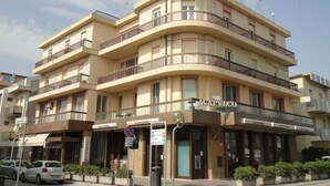 Um hotel com vários andares, varandas, uma entrada visível e a sinalização 'ACAPVLCO'.