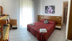 Um quarto com beliches, uma cama de solteiro, uma janela com cortinas e um quadro na parede.