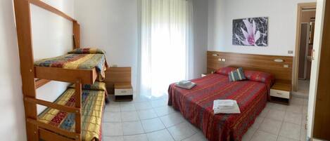 Una habitación con literas, una cama individual, un ventanal con cortinas y un cuadro en la pared.
