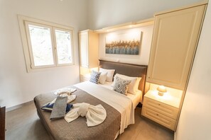 A bedroom with a bed, bedside tables, a window, and a wall-mounted artwork. - Villa Apanemia - Three Bedroom Villa, Sleeps 6 (Kassiopi)