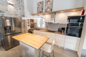 A modern kitchen with a wooden island, stainless steel appliances, and a stone accent wall. - Villa Apanemia - Three Bedroom Villa, Sleeps 6 (Kassiopi)