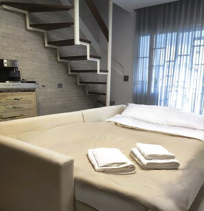 Een hotelkamer met een bed, een trap, een koffieapparaat en een bord aan de muur.
