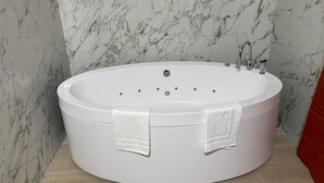 Et moderne badeværelse med et stort, ovalt badekar, marmorvægge og en rød detaljevæg.