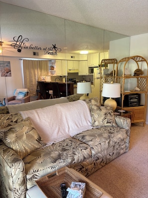 A living room with a sofa, a coffee table, a lamp, and a bookshelf. - Cozy Beach Escape (Ocean City)