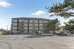 A multi-story apartment building with a parking lot in front. - Cozy Beach Escape (Ocean City)