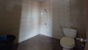 Un baño con ducha, inodoro y suelo de baldosas.