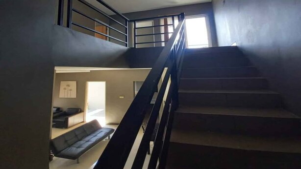 Una escalera con baranda de metal que lleva a un rellano en el segundo piso.