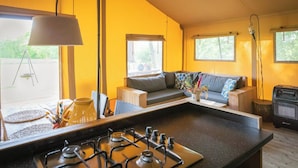 Een keuken met een gasfornuis, een eethoek met een tafel en stoelen, een bank met kussens, en een raam met uitzicht.