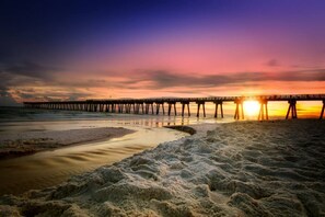 Ein Steg, der sich ins Wasser erstreckt, mit untergehendem Sonnenuntergang im Hintergrund.
