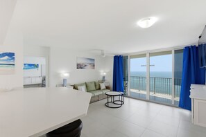 Ein modernes Wohnzimmer mit Balkon, weißen Möbeln und Kunstwerken an den Wänden.