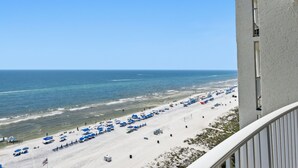 Ein Strand mit Sonnenschirmen und Liegestühlen, ein klarer Himmel und das Meer.