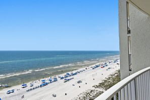Ein Strand mit Sonnenschirmen und Liegestühlen, ein klarer Himmel und das Meer.