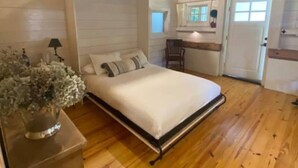 A wooden-paneled room with a bed, a desk, a chair, and a ceiling fan. - Canoe Club Studio - Bring you boat! dock slip available (Daufuskie Island)