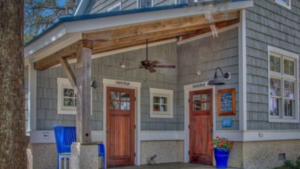 A two-story building with a porch, two wooden doors, and a blue chair outside. - Canoe Club Studio - Bring you boat! dock slip available (Daufuskie Island)
