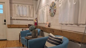 A room with a wooden ceiling, a blue armchair, a small table with a vase, and a patterned rug. - Canoe Club Studio - Bring you boat! dock slip available (Daufuskie Island)