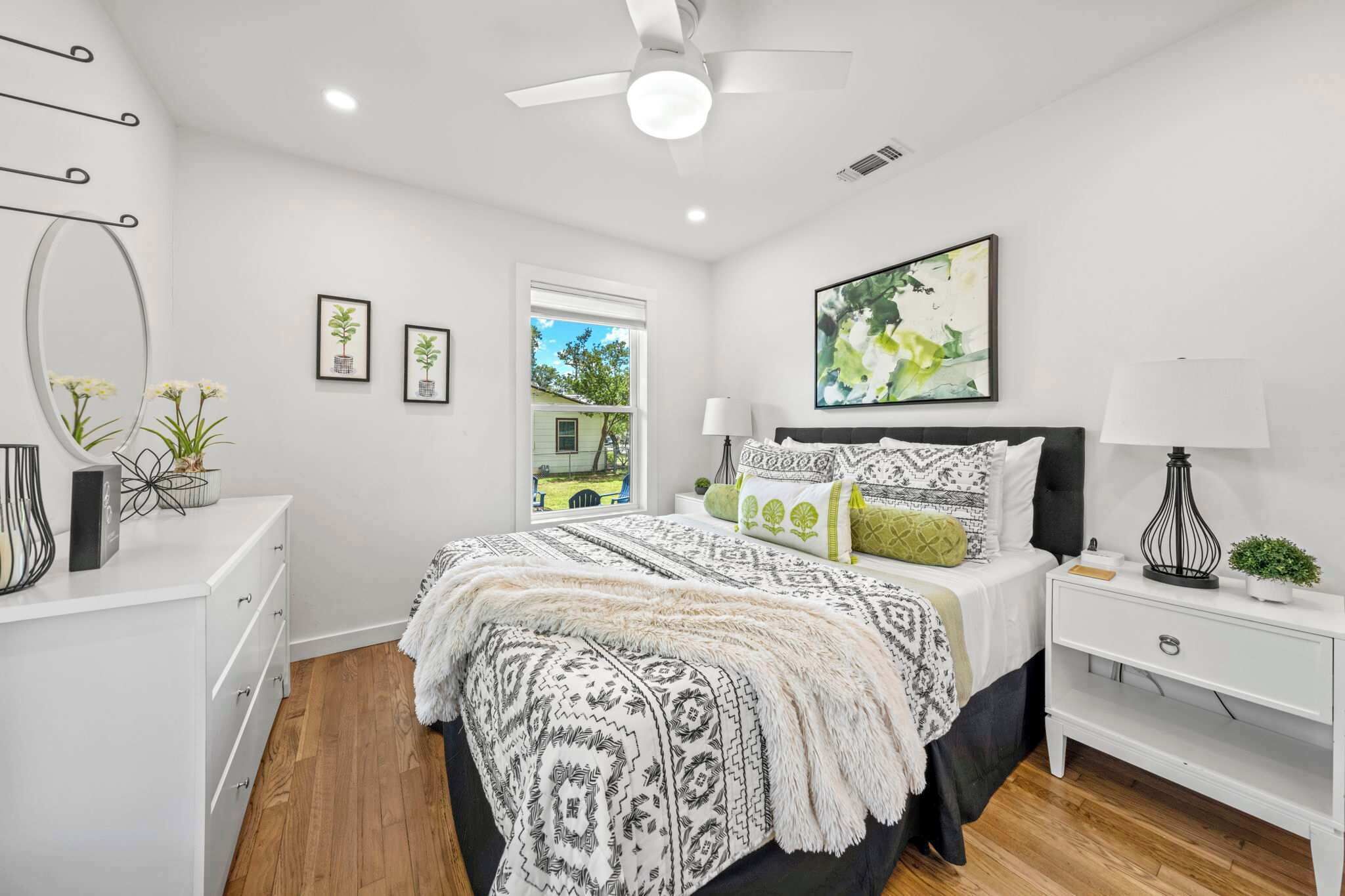 A bedroom with a bed, bedside tables, a ceiling fan, and a window.