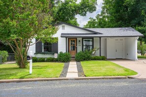A single-story house with a front door, a garage, and a mailbox. - Bottles & Boots on Burbank - Hot Tub & Fireplace (Fredericksburg)