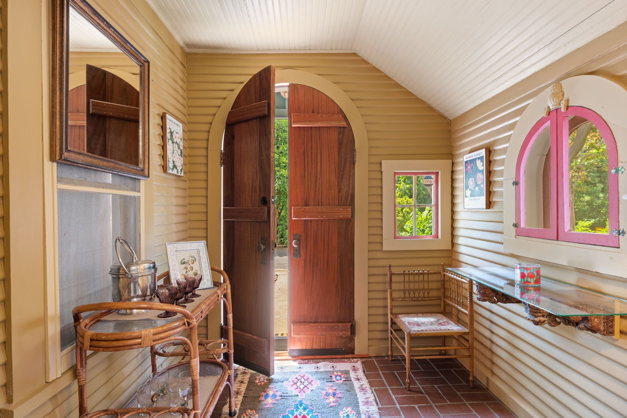Un intérieur chaleureux avec des portes en bois, un fauteuil en osier, une table en verre et une petite fenêtre.