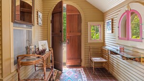 A cozy interior with wooden doors, a wicker chair, a glass table, and a small window. - Perla's Place - Fire Place & 3 Blocks from Main (Fredericksburg)
