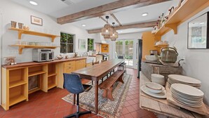 A spacious kitchen with wooden beams, a dining table, and a variety of kitchenware. - Perla's Place - Fire Place & 3 Blocks from Main (Fredericksburg)