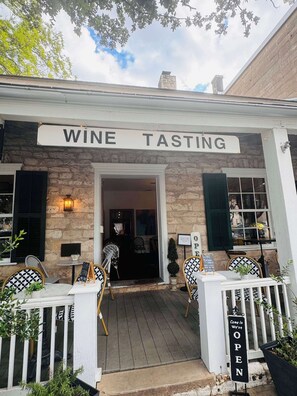 A building with a sign reading 'WINE TASTING' and a sign indicating the establishment is open. - Nimitz Loft - 1855 Historic Loft on Main St! (Fredericksburg)