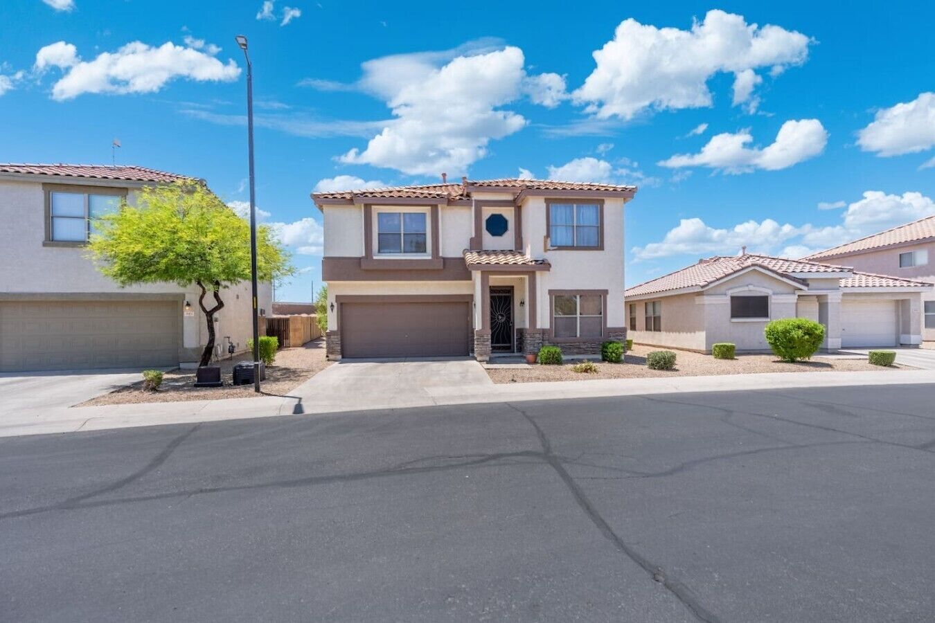 A two-story house with a garage, a small front yard, and a clear blue sky.