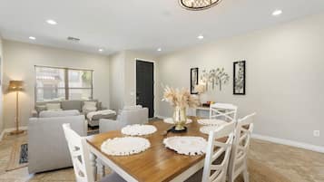 A dining area with a wooden table, white chairs, and a chandelier.