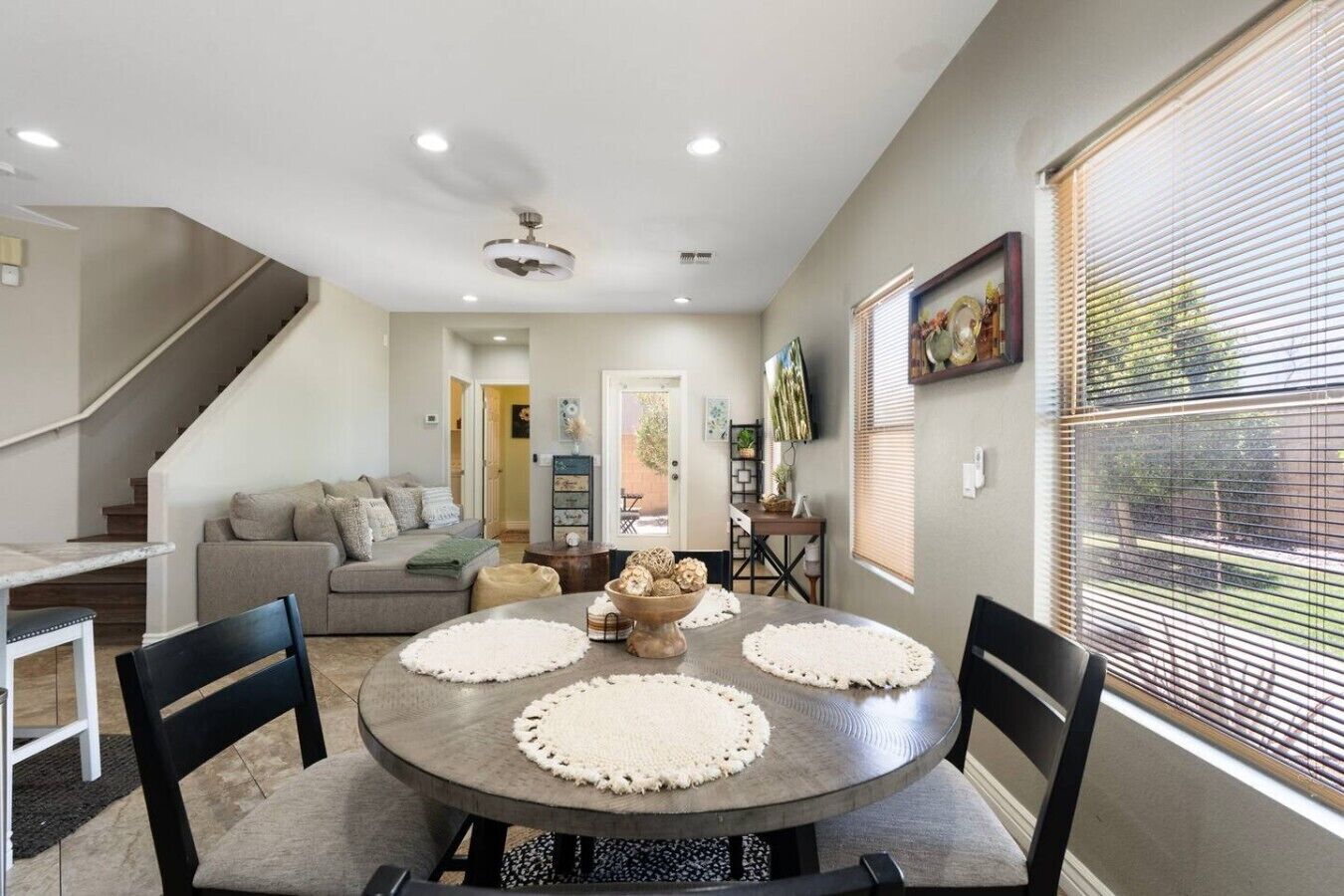 Un comedor con una mesa redonda, cuatro sillas y un ventilador de techo.