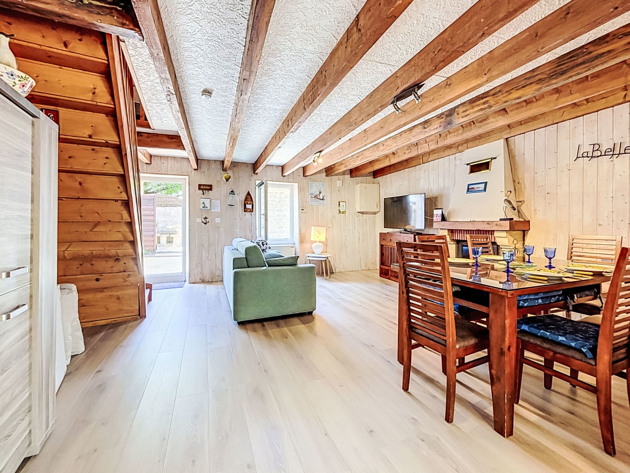 Un intérieur en bois comprenant une table à manger, des chaises, un canapé et un téléviseur.