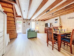 Un interior de madera con una mesa de comedor, sillas, un sofá y un televisor.