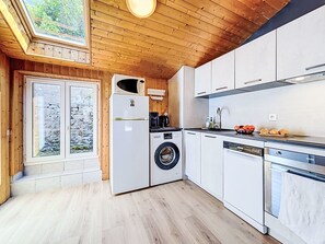 Eine moderne Küche mit Holzwänden, einer integrierten Waschmaschine und einem Geschirrspüler.