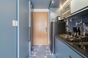 A narrow kitchen with a refrigerator, coffee maker, and a microwave. - Barra Premium by Carpediem Close to the Beach, Farol da Barra, and Barra Shopping (Salvador)
