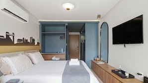 Een hotelkamer met een bed, televisie, kast en spiegel.