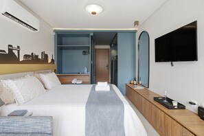 Ett hotellrum med en säng, en tv, en garderob och en spegel.