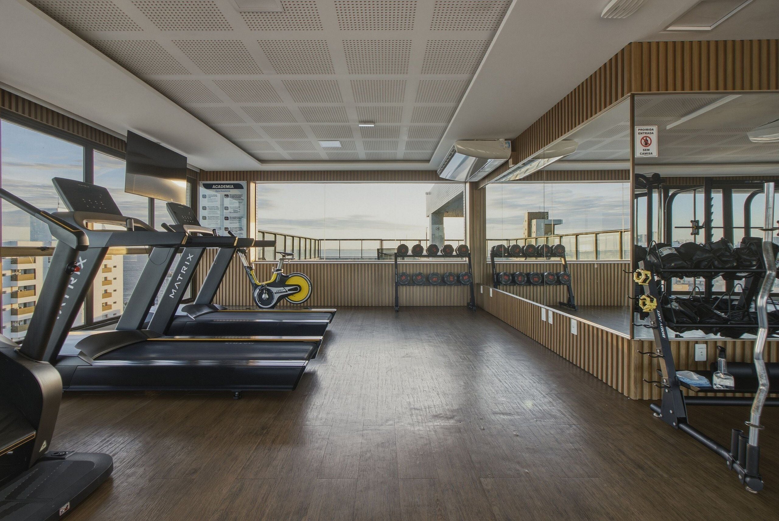 Une salle de sport équipée de tapis de course, d’un vélo d’appartement et de matériel de musculation.
