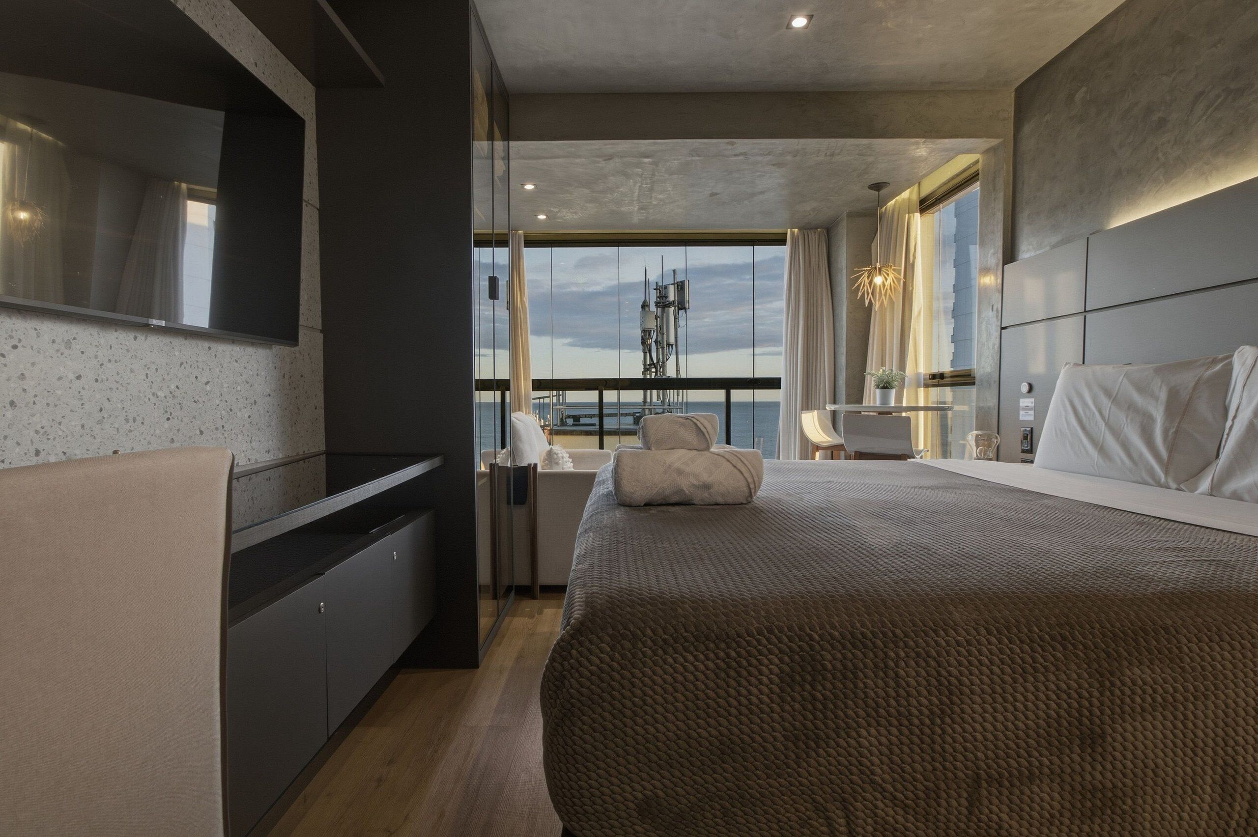 Une chambre moderne dotée d’un grand lit, d’un téléviseur intégré, d’un balcon avec vue et d’un design minimaliste.