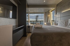 Quarto moderno com cama grande, televisão integrada, varanda com vista e design minimalista.