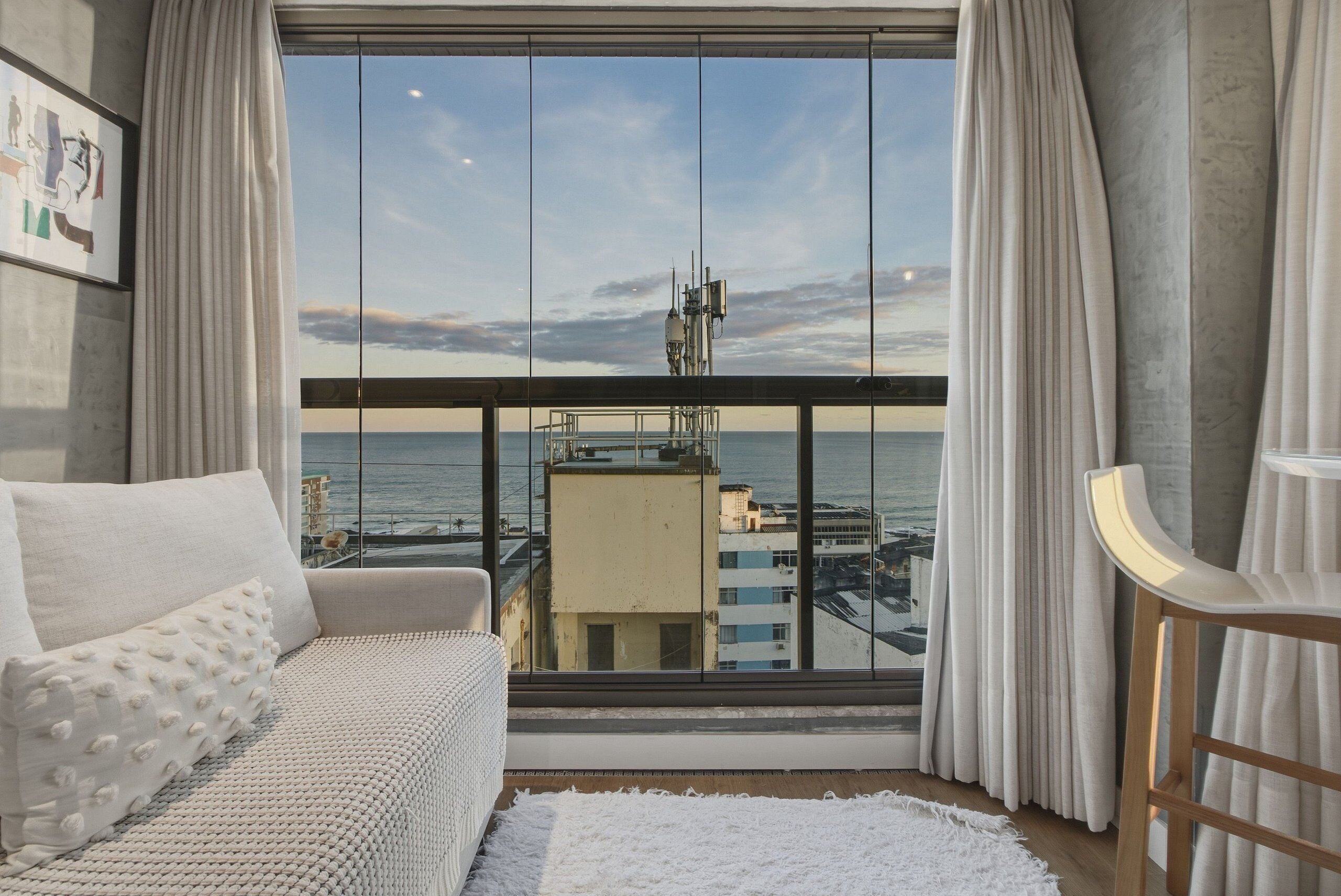 Un moderno salón con un amplio ventanal, un sofá y vistas a la ciudad y al agua.