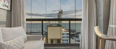 Un moderno salón con un amplio ventanal, un sofá y vistas a la ciudad y al agua.