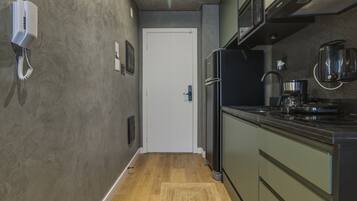 A kitchen with a refrigerator, microwave, coffee maker, and a phone on the wall.