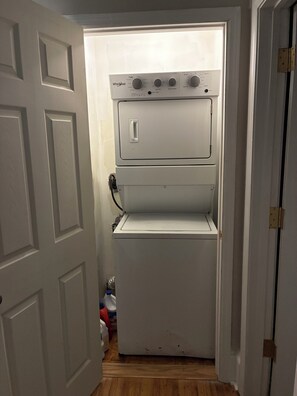 Un lave-linge et un sèche-linge Whirlpool compacts et blancs, installés dans un couloir étroit doté d’un plancher en bois.