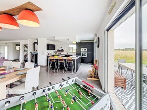 Um espaço de estar moderno com mesa de futebol, cozinha e área de jantar.