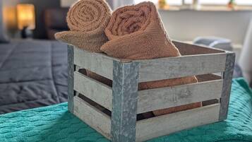 A rustic wooden crate with two rolled towels on top, placed on a teal blanket.