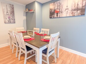 A dining area with a round table, white chairs, and red placemats.
