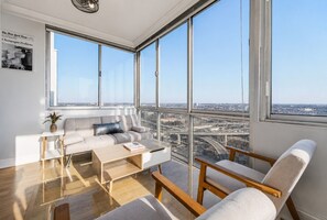 Un salon moderne avec une grande fenêtre, un canapé, une table basse et un fauteuil.