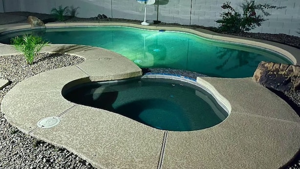 A swimming pool with a curved design, a basketball hoop, and a small palm tree. - Tempe Oasis w Pool, Spa and Garage! (Tempe)