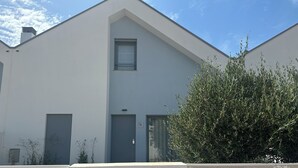 Un edificio moderno con techo plano, una ventana pequeña y una puerta con panel de control de acceso.