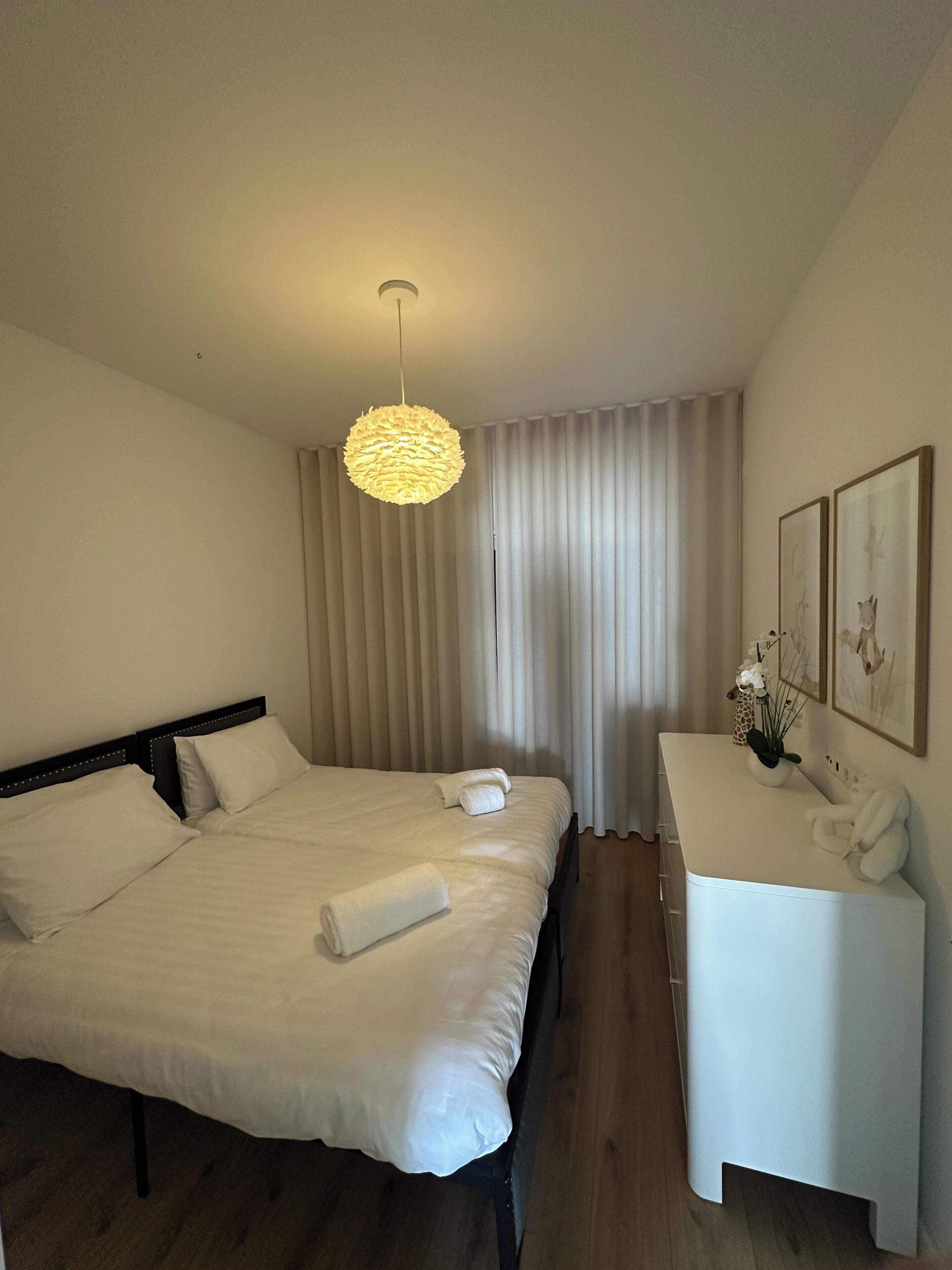 A hotel room with a bed, bedside table, and a hanging light fixture.