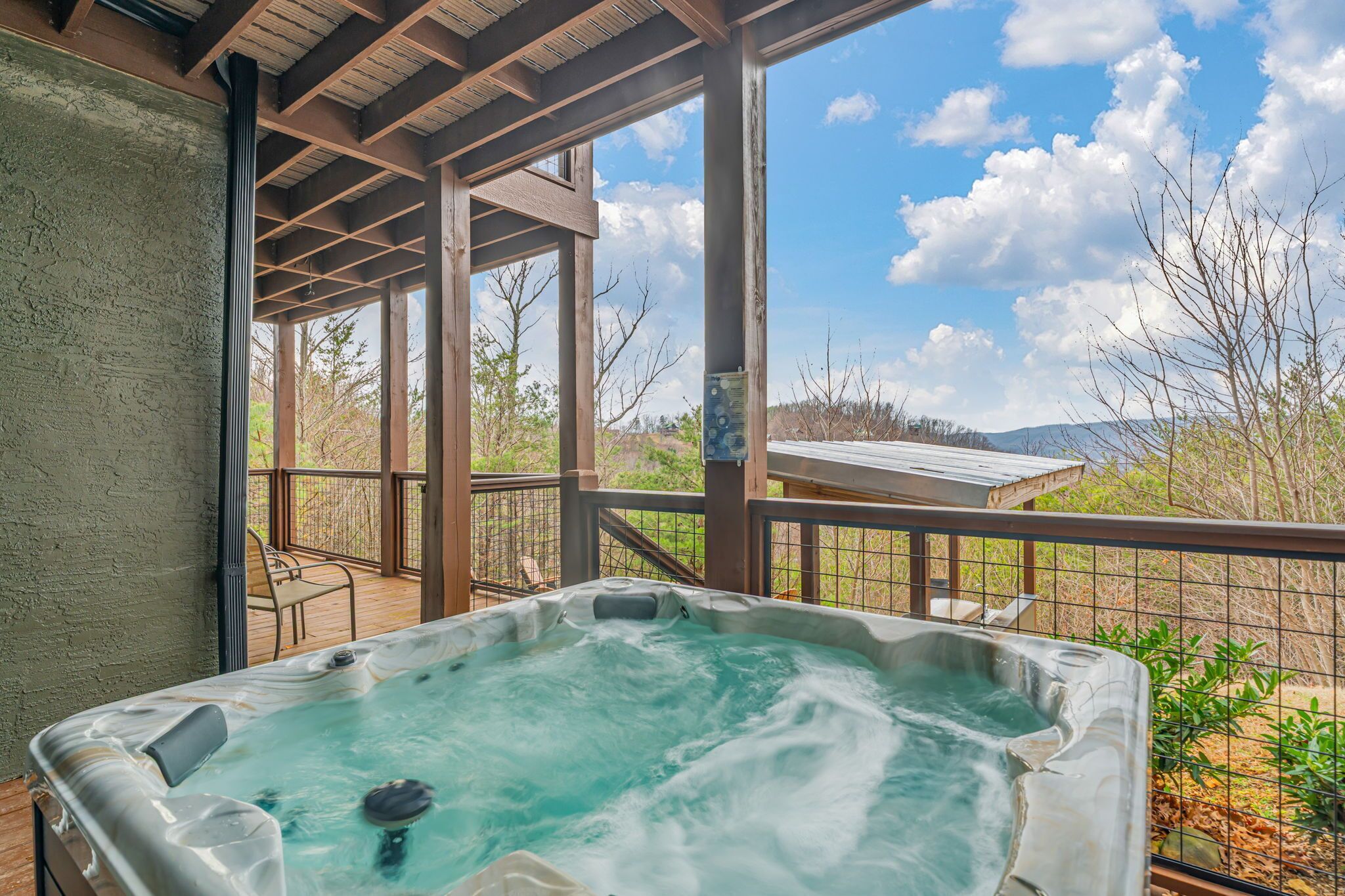 A hot tub on a wooden deck with a view of trees and mountains.